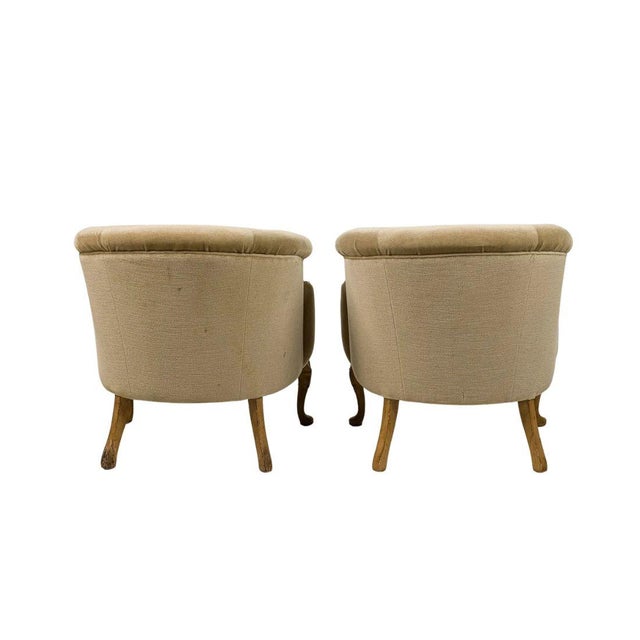 A pair of Louis XV style bergere chairs featuring gracefully curved backs, enveloping upholstered arms, and carved...
