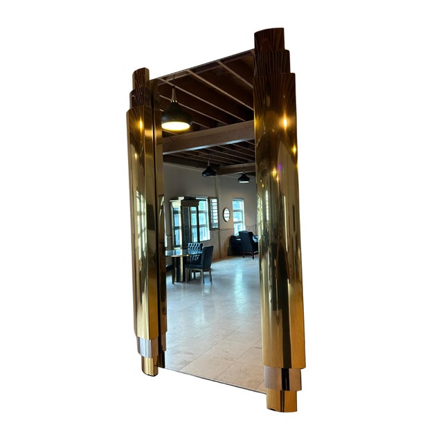 A striking vintage wall mirror featuring dramatic sculptural brass columns on each side, capped with contrasting chrome...