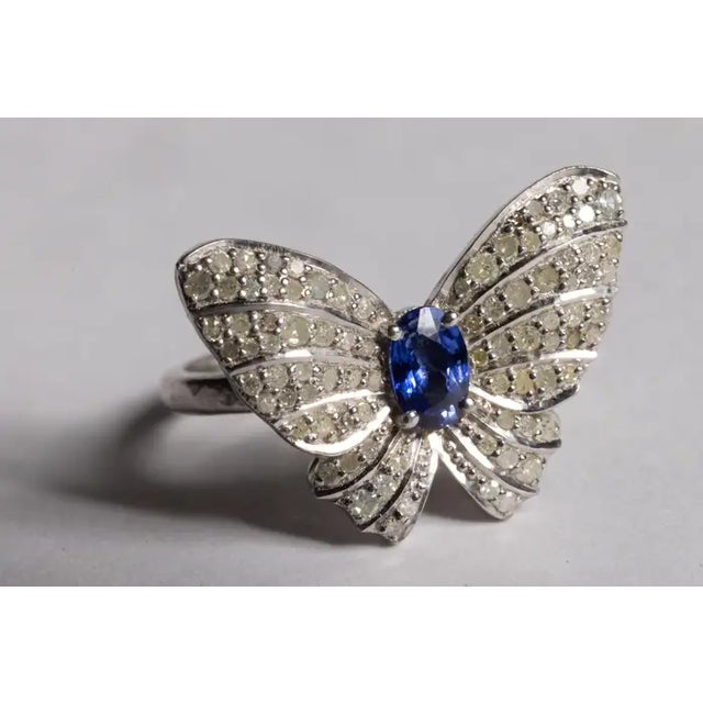 A fun butterfly motif ring featuring a center, round faceted blue sapphire and round, brilliant cut diamonds comprising...