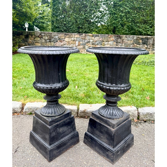 A substantial pair of English cast iron garden urns on their original square plinths, dating to circa 1880. Of classic...