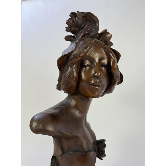 This bronze bust portrays a serene female figure crowned with flowing organic forms that appear to blossom from her hair...