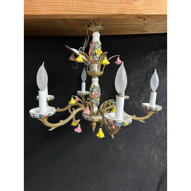 A wonderfully ornate vintage six-light chandelier combining richly detailed porcelain floral decoration with scrolling...