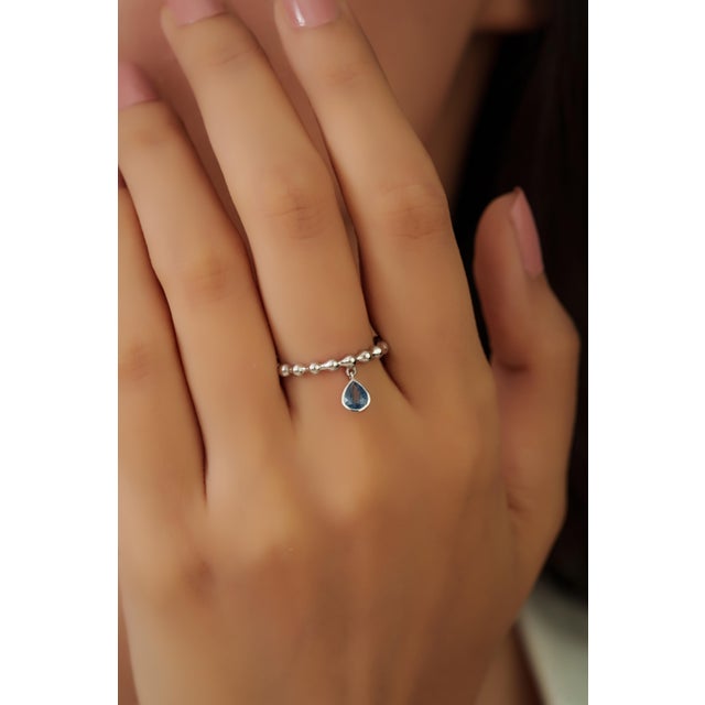 This beaded charm ring features a 0.43 carat pear-shaped blue sapphire set in 14k white gold. The sapphire measuring 3.5 x...