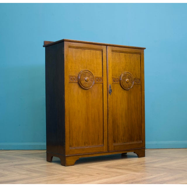 Compact 1930s oak gentleman’s wardrobe with carved roundel decoration, panelled doors and fitted interior. The layout...