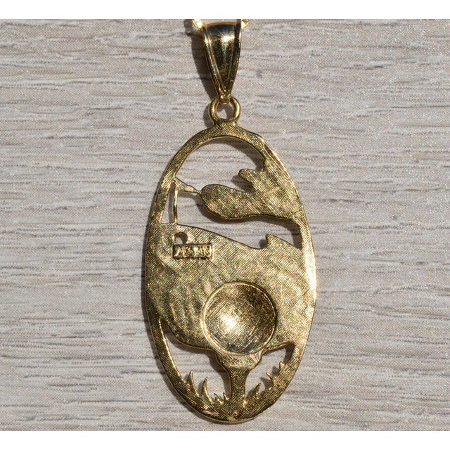 The Woods: Signed Gold Pendant in Yellow Gold. The pendant features a pimpled golf ball with driver behind and greens with...