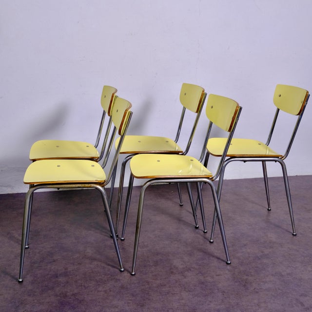 This beautiful set of 5 chairs features a bright pastel yellow Formica seat and backrest, with an elegant dark edge...