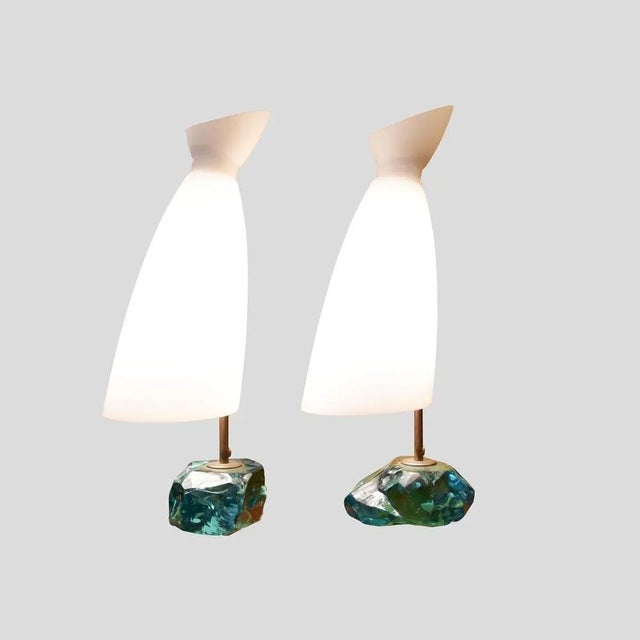 A pair of table lamps, with brass structure on cut glass pedestals with white satin blown glass shades designed by Roberto...