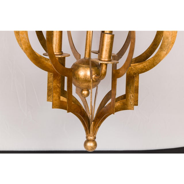 A French gilt metal lantern from the mid 20th century with three lights, scrolling effects and sphere motif. This...