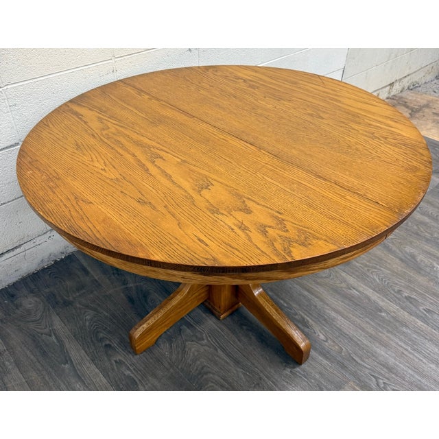 This is a vintage, possibly antique, solid oak round pedestal dining table featuring a classic Mission Arts and Crafts...