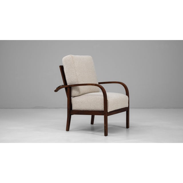 20th century French Art Deco upholstered armchair featuring a reclining backrest and the elegant curvature typical of the...