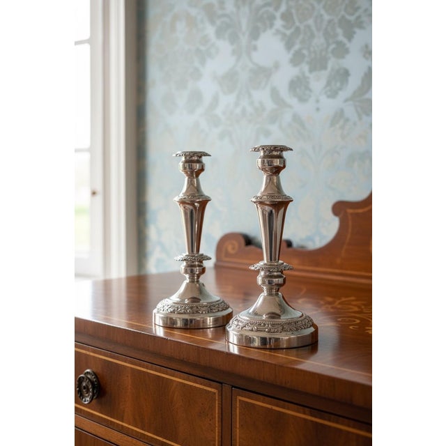 A handsome pair of vintage silverplate candlesticks featuring classic repoussé decoration with scrolling foliate detail at...