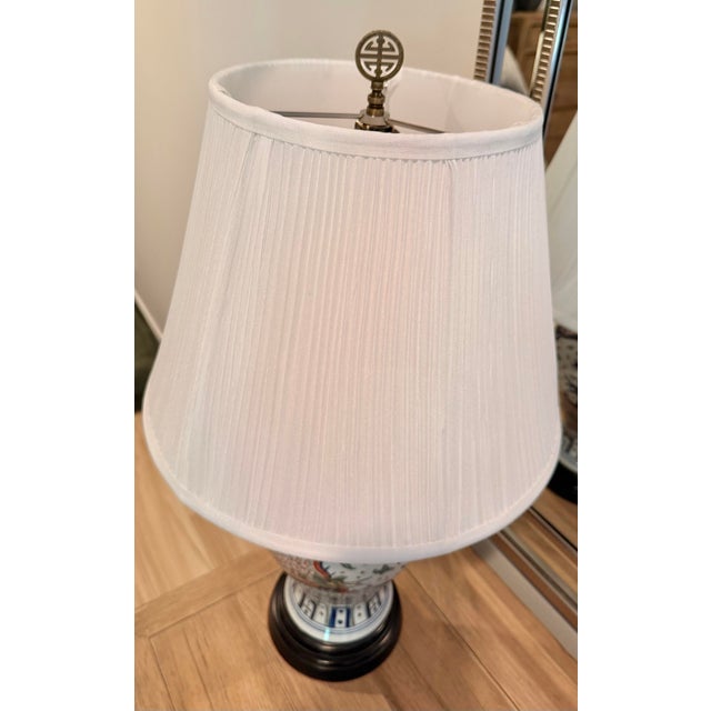 Striking vintage Asian porcelain table lamp featuring colorful hand-painted dragon and phoenix motifs over an intricate...