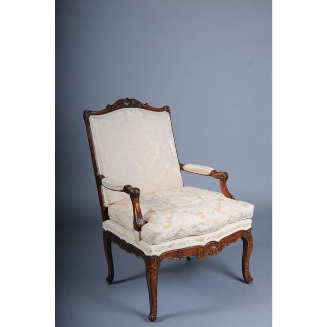 Stately French oak armchair in the Louis XV style. Solid wood, richly carved frame with curved legs and armrests. High,...