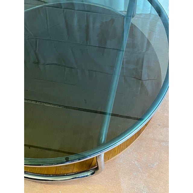 1970s coffee table made in Italy. Chromed metal frame, smoked glass top, and a wooden lower shelf.