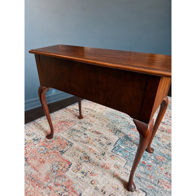 Beautiful side table in burled walnut by Baker featuring Queen Anne-style legs. Its three drawers are elevated with ornate...