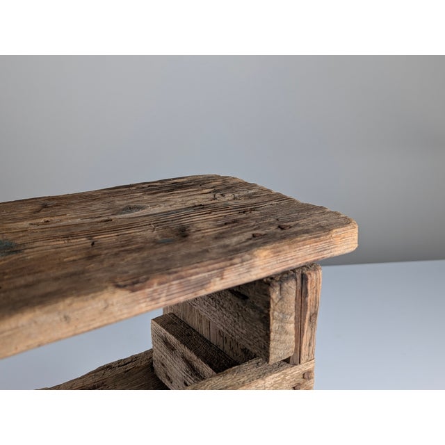 A rustic wooden bench or stool, crafted using traditional methods, whose aesthetic pays tribute to simplicity and the...
