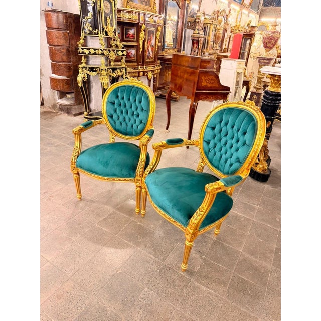 A striking matching pair of French Louis XVIstyle fauteuil armchairs, featuring richly carved gold-finished frames and...