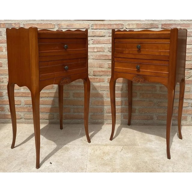 A fine pair of French bedside end tables or nightstands - each Stand featuring a scalloped edge gallery over a frieze of...