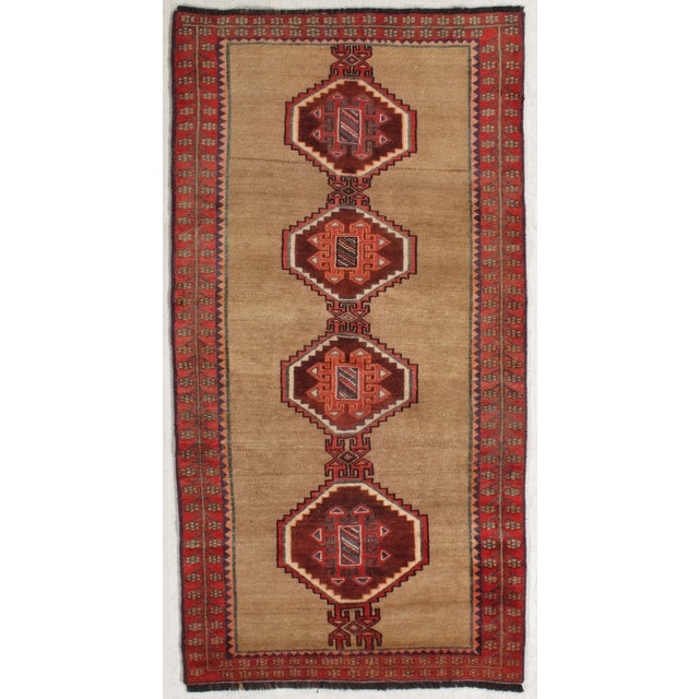 Antique Persian Gabbeh hand-knotted wool rug featuring a warm camel-toned field with a vertical row of bold geometric...