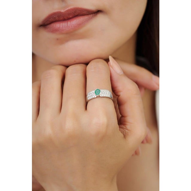 Crafted in 925 sterling silver, this elegant ring features a vibrant 0.47 carat oval-cut emerald accented by sparkling...