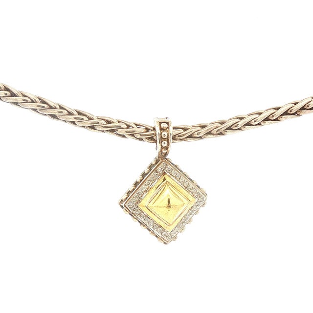 A striking pendant necklace featuring a 18k gold centerpiece. The pendant is framed by a border of white diamonds, adding...