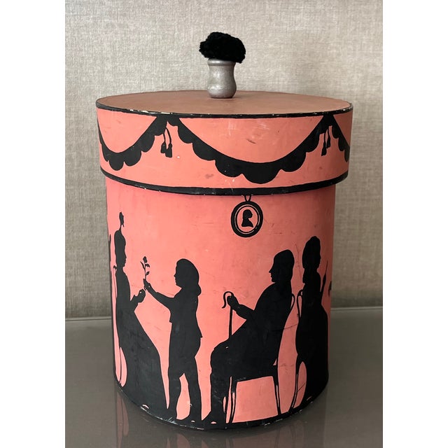 Vintage oval wallpaper box by Atelier of Hudson, New York with black Regency silhouettes on a pink ground. Depicts scenes...
