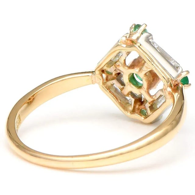 Emeralds and diamonds gleam in a distinct pattern from the center of this splendid geometric ring. Brightly colored yellow...