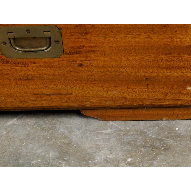 An English camphor wood Campaign low chest from the 19th century, with three drawers and inset brass hardware. Created in...