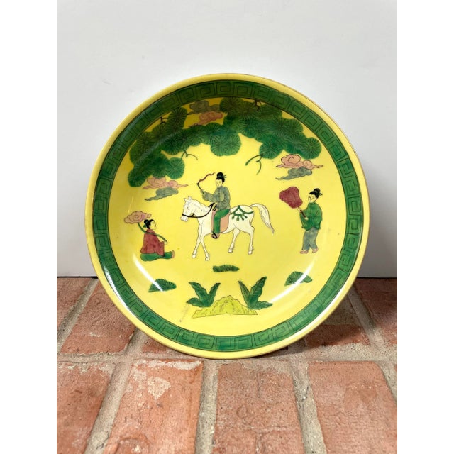 Decorative Japanese porcelain shallow bowl hand-decorated in Hong Kong with a figural scene, vibrant green foliage, and a...