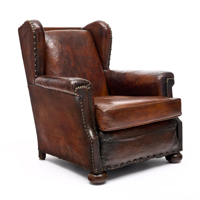 French vintage wing-back club chair with original mahogany leather and nail head trim. It is supported by bun feet. This...