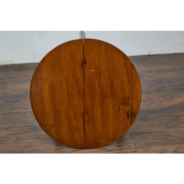 An English pine cricket table from the 19th century with circular top, tripod base and triangular low shelf. This English...