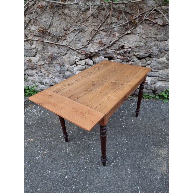 Vintage French pine table dating from the 1930s. This lightweight table features turned beech legs and a solid pine top...