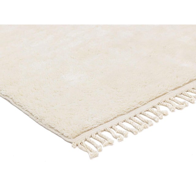 A pure, sumptuous ivory field, rich with the natural texture and gentle tonal variation that only hand-knotted wool can...