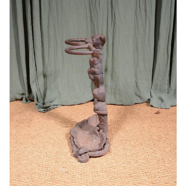 A heavy cast iron stick stand to a design by Coalbrookdale, in the form of a dog holding a hunting whip in its jaws, on a...