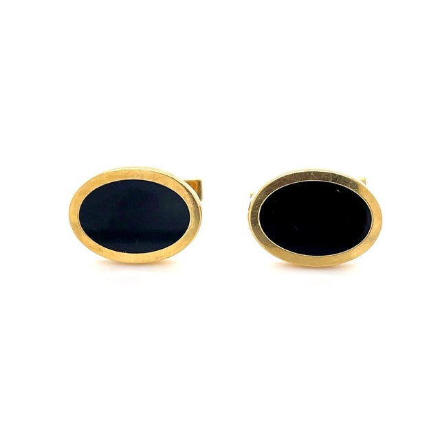 A pair of classic Tiffany & Co. cufflinks with oval onyx inlay and high polish yellow gold finish. Accompanied by a...