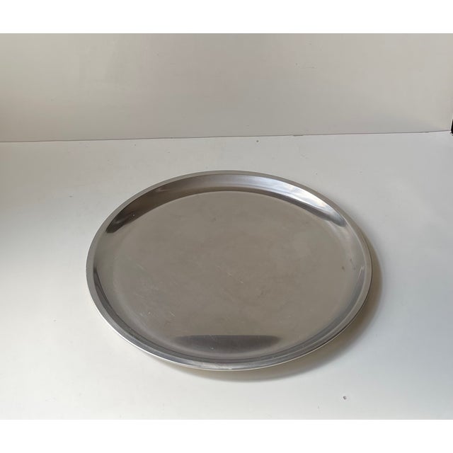 A circular 35 cm serving tray in stainless steel. Designed and made by jeno - danish design in denmark circa 1970-75. A...