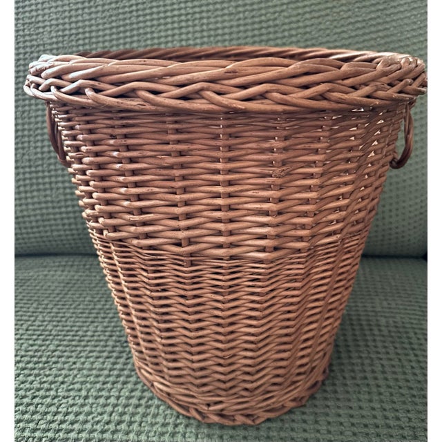 Vintage wicker wastebasket. 13” wide at the top and 14” tall. It has a tapered silhouette with a substantial reinforced...