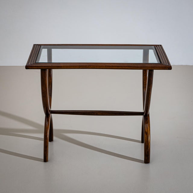 Side table featuring a rectangular top with a glass insert and a wide, ribbed frame. The top is supported by a scissor-...