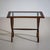 Side table featuring a rectangular top with a glass insert and a wide, ribbed frame. The top is supported by a scissor-...