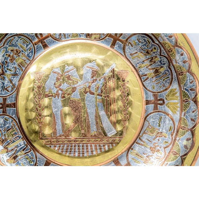 Egyptian Revival Round Brass Tray with Silver and Copper Overlay Wall Hanging. Dimensions: 8.75 in. diameter. Label in the...