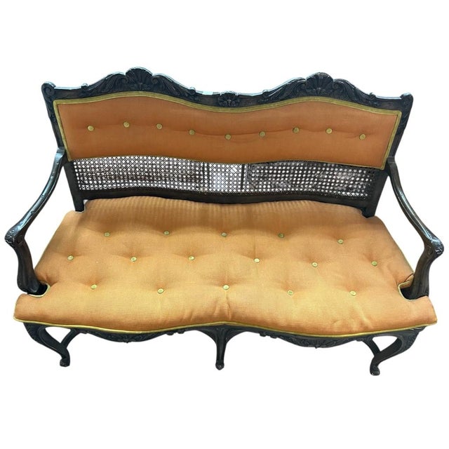 Elegantly carved wood settee featuring a dark finish with intricate floral details and caned back panel. The frame is...