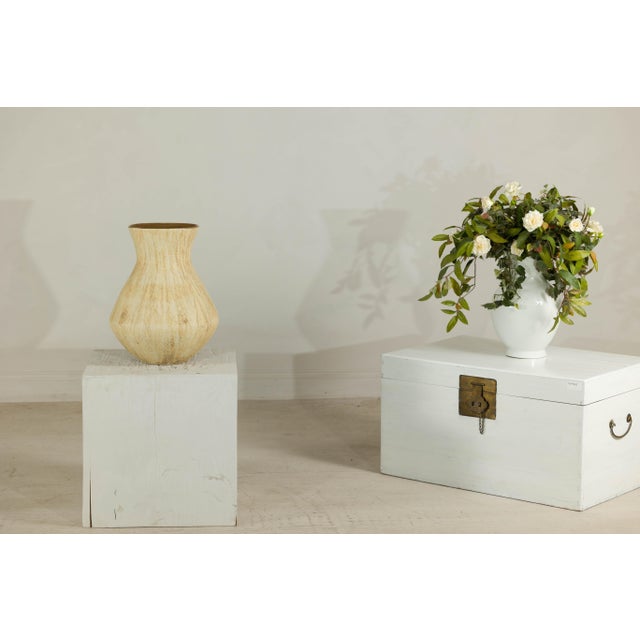This large artisan ceramic vase presents a sculptural, organic form enhanced by a richly textured surface and warm neutral...