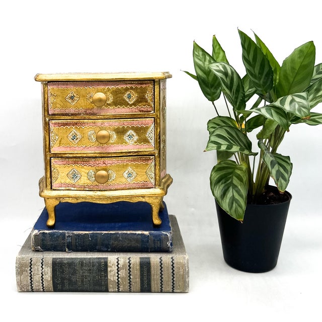 Stunning, vintage Italian Florentine miniature three-drawer chest featuring a hand-decorated pink and gold finish with...