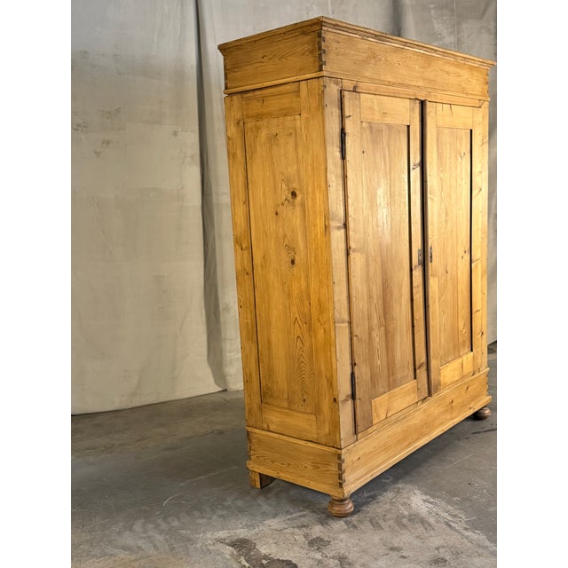 A handsome 19th-century Dutch pine wardrobe with beautifully simple paneled doors, dovetailed construction and turned bun...