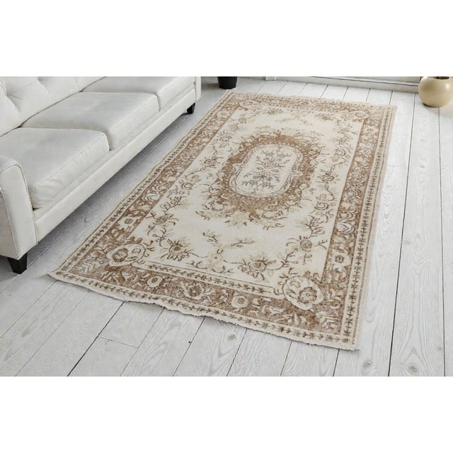 This is a vintage Turkish Oushak rug from the Mid 20th Century. The piece was hand-knotted.