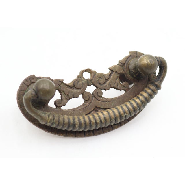 Vintage Victorian drawer pulls made of brass with a dark patina. They feature scrollwork, filigree patterns, and ribbed...