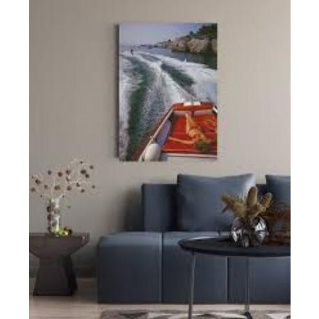 A woman sunbathing in a motorboat as it tows a waterskiier, in the sea off the Hotel du Cap-Eden-Roc in Antibes on the...