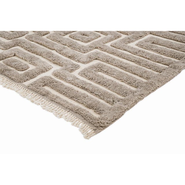 This hand-knotted Moroccan wool rug features a dense, maze-like geometric pattern rendered in crisp ivory against a rich,...