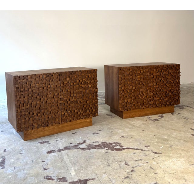 Pair of 20th-century Brutalist-style wooden sideboards. Italy. The sideboards feature double doors, and the fronts of the...