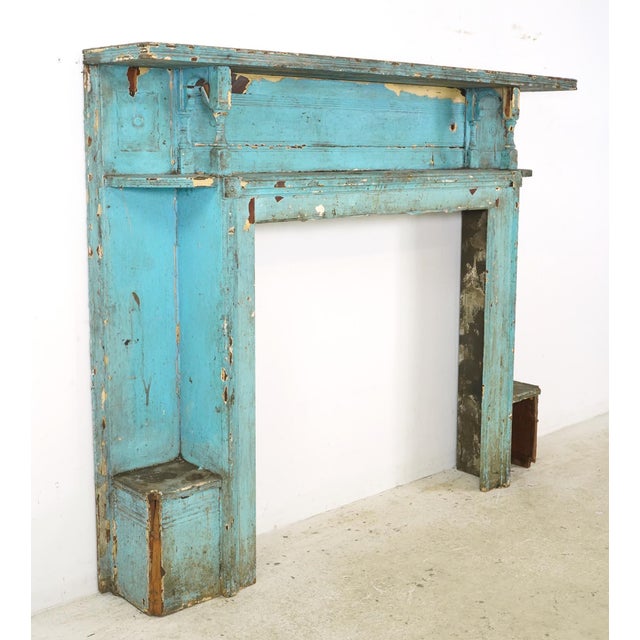 Georgian style fireplace mantel made of blue painted wood. It features a fluted frieze and jambs with bullseye block ends....